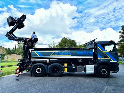Neuer LKW mit Bagger, Fahrer auf dem Bagger
